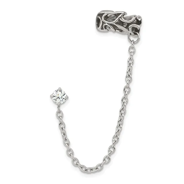 A silver decorative ear cuff with ornate swirling details connected by a chain to a cubic zirconia charm, displayed against a white background.