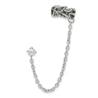 A silver decorative ear cuff with ornate swirling details connected by a chain to a cubic zirconia charm, displayed against a white background.
