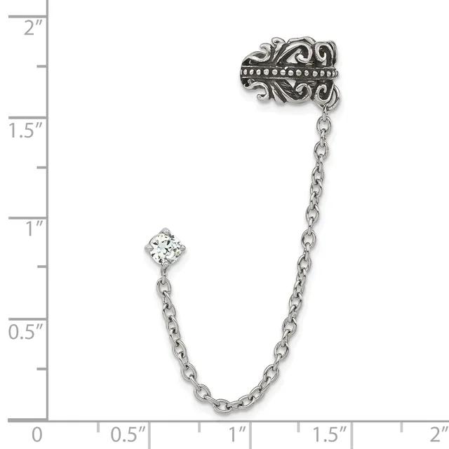 Silver-tone ornate brooch with dangling chain and clear crystal stone, shown against a ruler measuring approximately two inches in length.