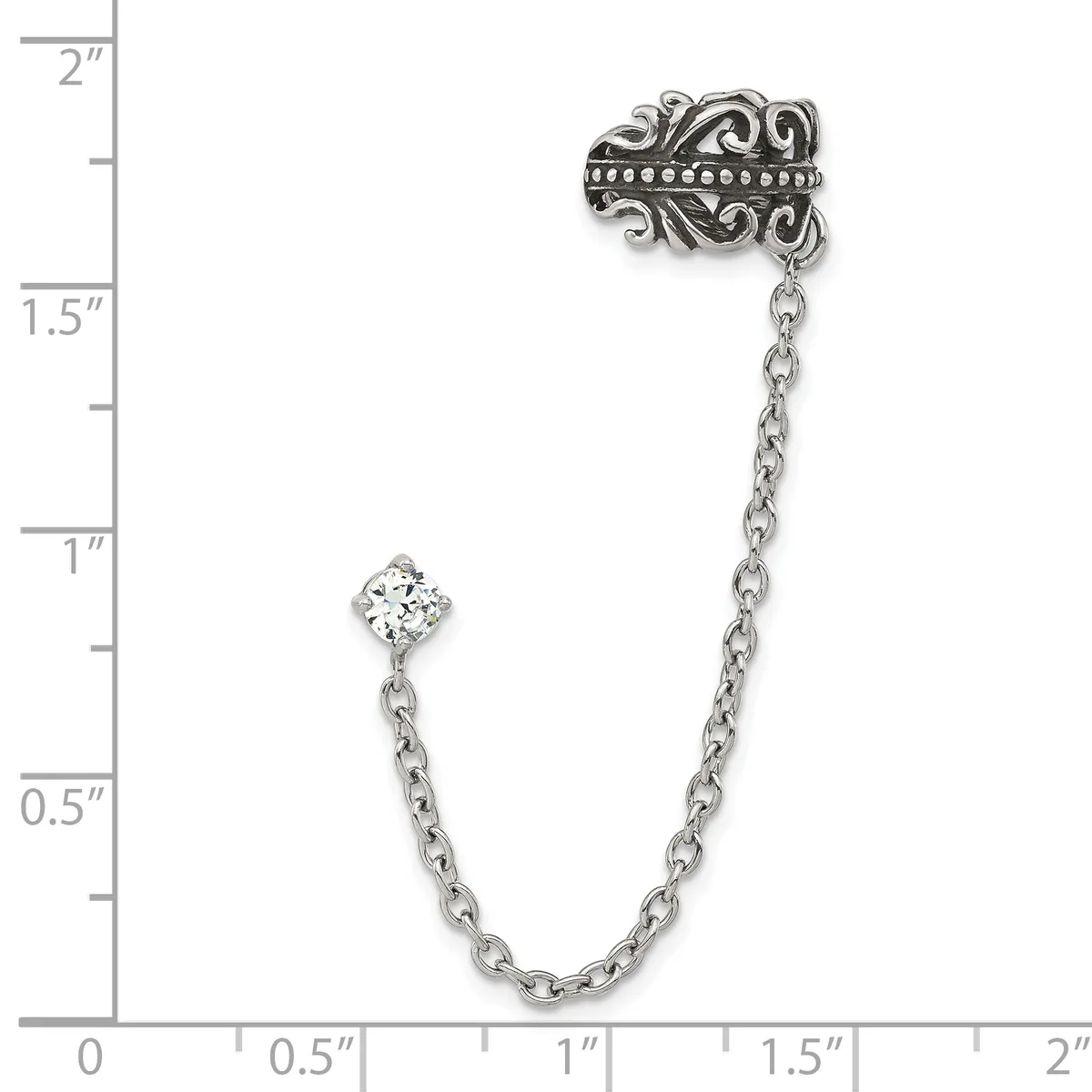 Silver-tone ornate brooch with dangling chain and clear crystal stone, shown against a ruler measuring approximately two inches in length.