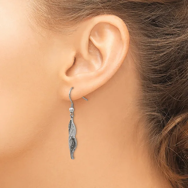 A person wearing a long, thin silver-toned dangle earring with a twisted spiral design hangs from a fish hook ear wire.