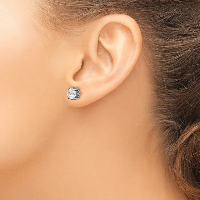 A woman wearing a small square stud earring with a clear faceted stone in a silver-toned setting, shown from the side view near her ear.