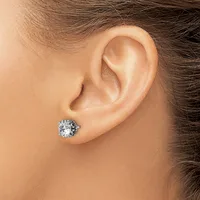 A close-up side view of a person's ear wearing a silver stud earring with a round clear gemstone in an ornate setting.
