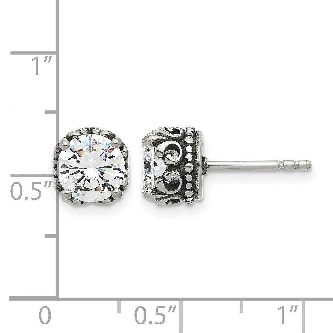 A pair of silver stud earrings with round clear gemstones in ornate filigree settings, shown against a measurement scale.