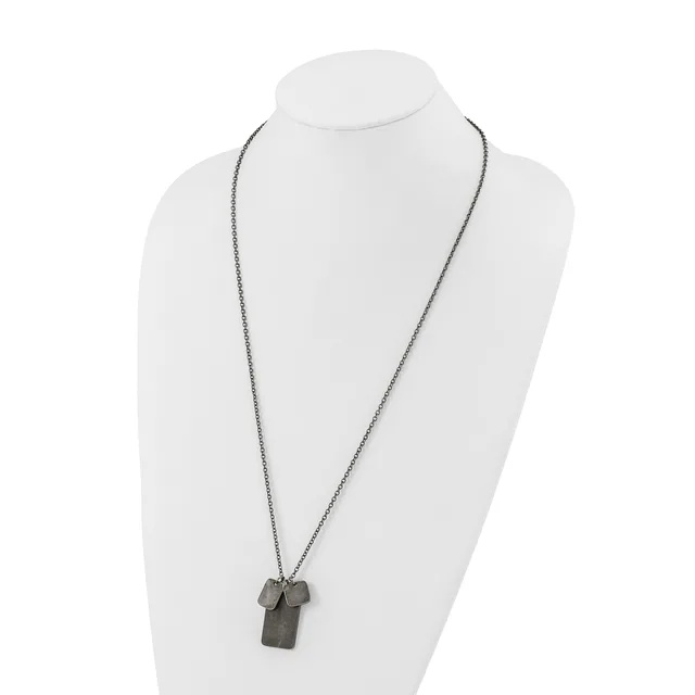 A long silver-toned chain necklace with a rectangular pendant and small geometric charms displayed on a white bust form.