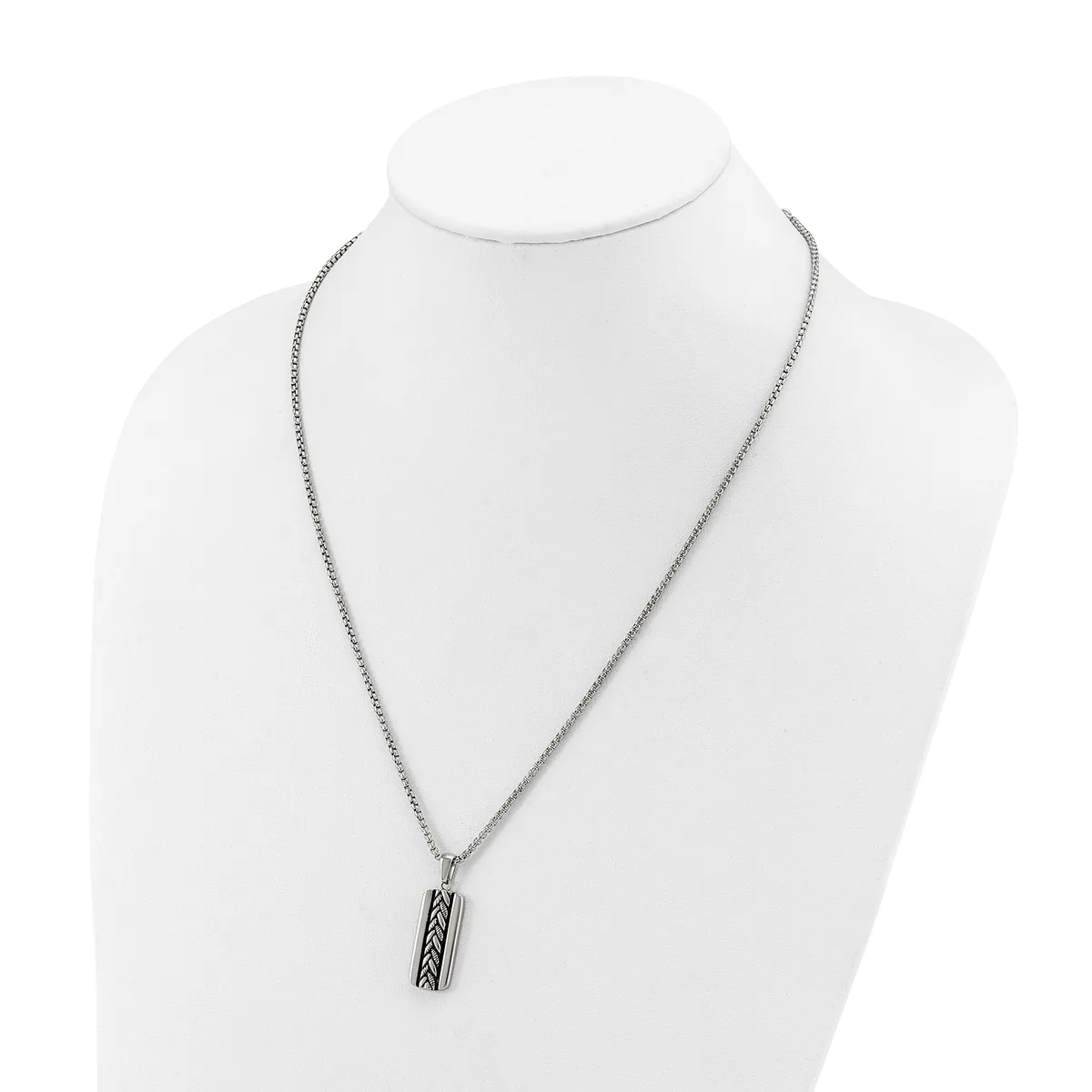 A silver-toned chain necklace with a rectangular pendant featuring a geometric crosshatch pattern, displayed on a white mannequin bust.