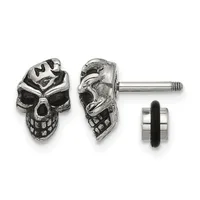Pair of silver skull stud earrings shown from front and side views with a rubber backing post displayed separately.