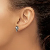 A silver stud earring with an ornate leaf or floral design worn on a person's earlobe, shown in close-up against their neck and shoulder.