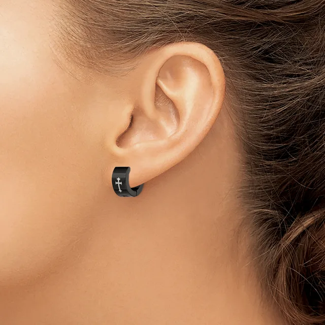 A person wearing a small black hoop earring with a silver cross design, shown from the side view of their ear and neck.