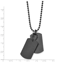 Two black metal dog tags with rounded corners hang from a black beaded ball chain necklace, displayed against a measurement scale.