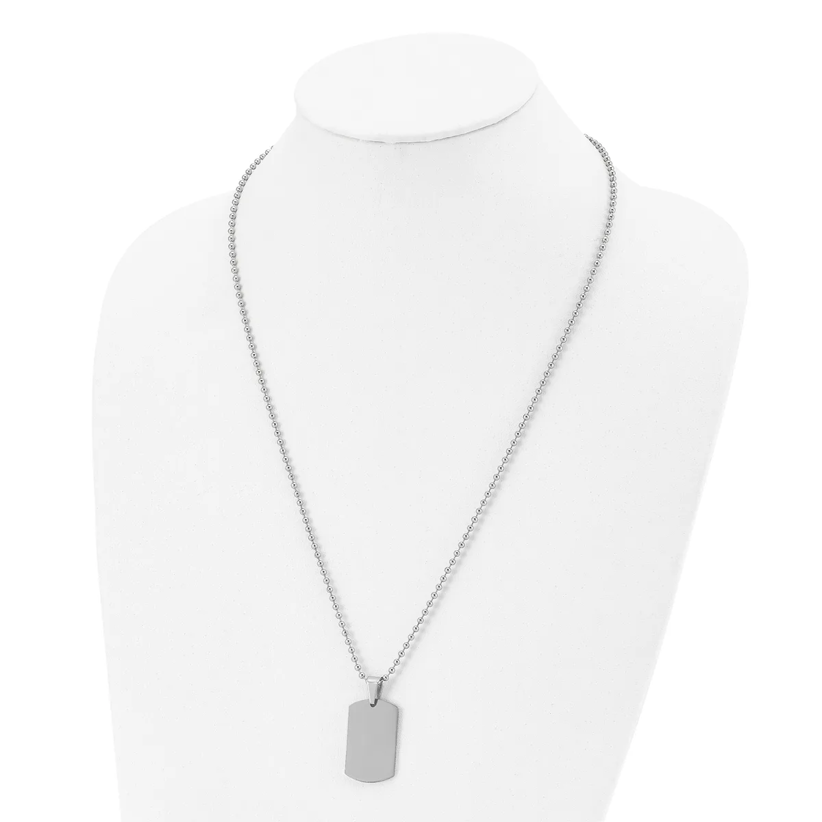 A silver-toned chain necklace with an attached rectangular dog tag pendant displayed on a white bust form.