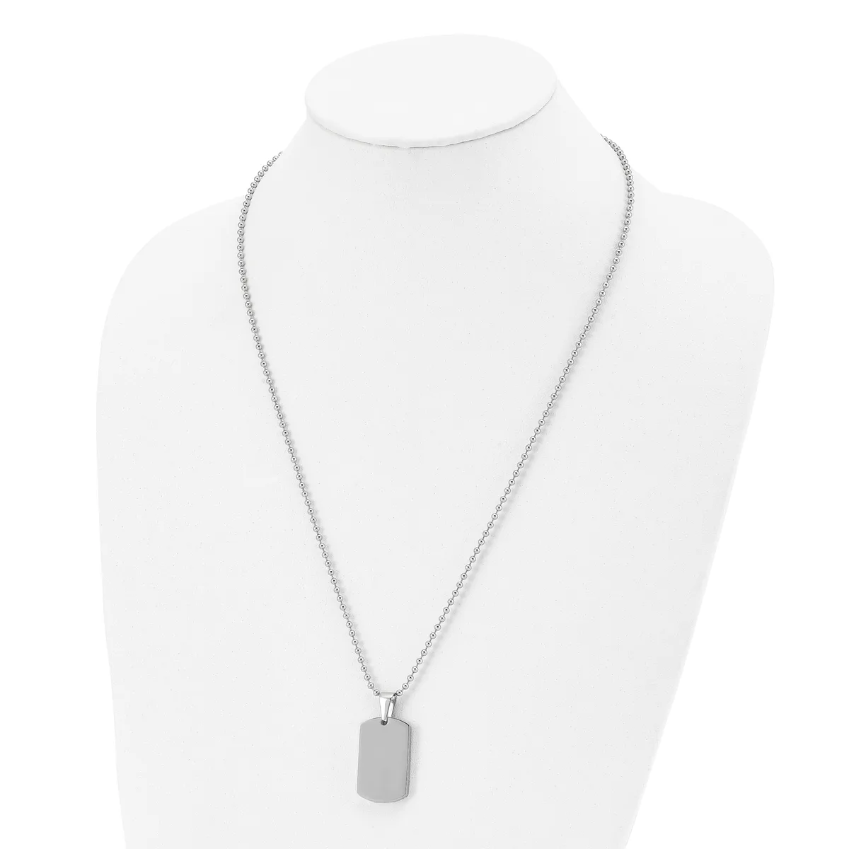 A silver-toned rectangular pendant hangs from a delicate chain on a white mannequin bust.