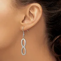 A woman wearing a pair of silver-toned figure-eight drop earrings with French wire hooks.
