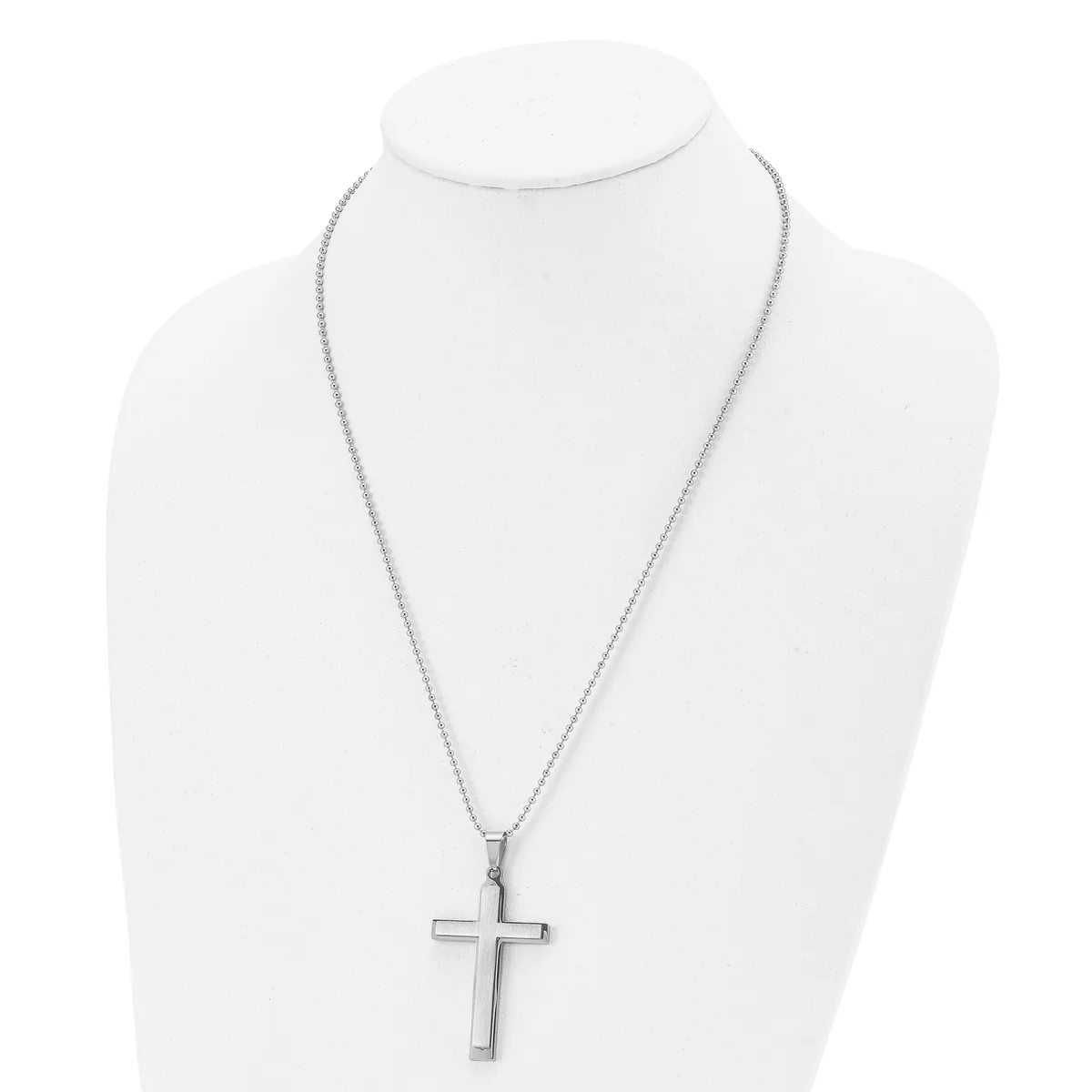 A silver-toned cross pendant hangs from a delicate chain on a white display bust form.