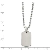 A brushed stainless steel dog tag pendant hangs from a ball chain necklace, displayed against a measurement scale showing approximately 2.5 inches in length.