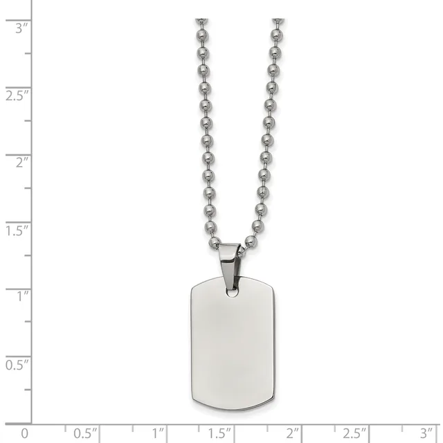 A stainless steel dog tag pendant hangs from a ball chain necklace, displayed against a measurement scale showing the pendant is approximately one inch wide and one and a half inches tall.