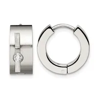 Two silver hoop earrings displayed against a white background: one wide polished hoop with a geometric cutout design, and one rectangular brushed silver earring with vertical grooves and a centered round crystal.