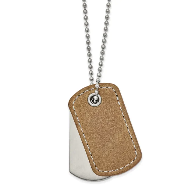 A dog tag pendant with a tan leather front panel and polished metal back, suspended from a beaded chain.