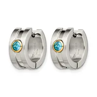 A pair of stainless steel hoop earrings with gold-tone bezels holding round blue topaz stones, shown from the front and back.