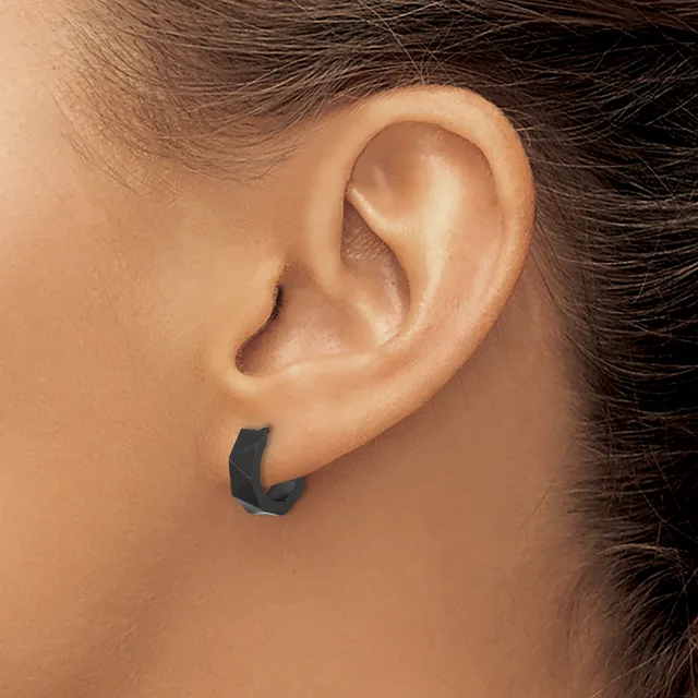 A person wearing a black curved hoop earring in their lower earlobe, shown in profile view.