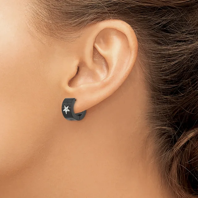 A person wearing a black crescent moon-shaped earring with a white star cutout, shown from the side view of their ear and neck.