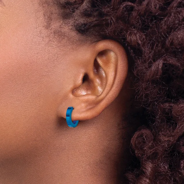 A blue curved hoop earring worn on the earlobe of a person with dark curly hair shown in profile.