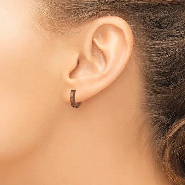 A person wearing a small curved hoop earring in their earlobe, shown in close-up profile view.