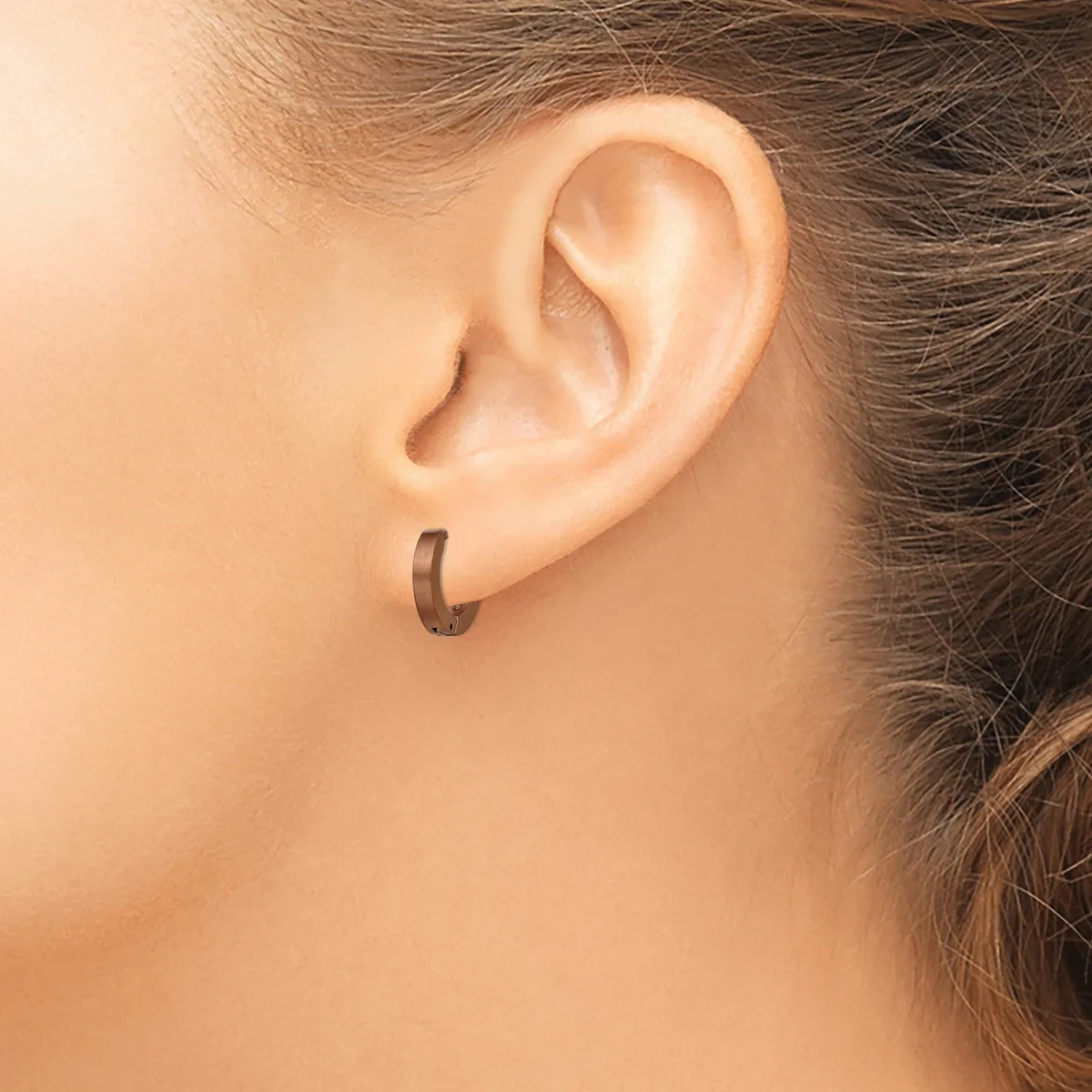 A person wearing a small curved hoop earring in their earlobe, shown in close-up profile view.
