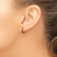 A person wearing a small curved hoop earring in their earlobe, shown in close-up profile view.