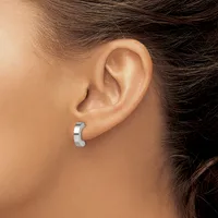 A person wearing a polished silver curved hoop earring in their pierced earlobe, shown in profile view.