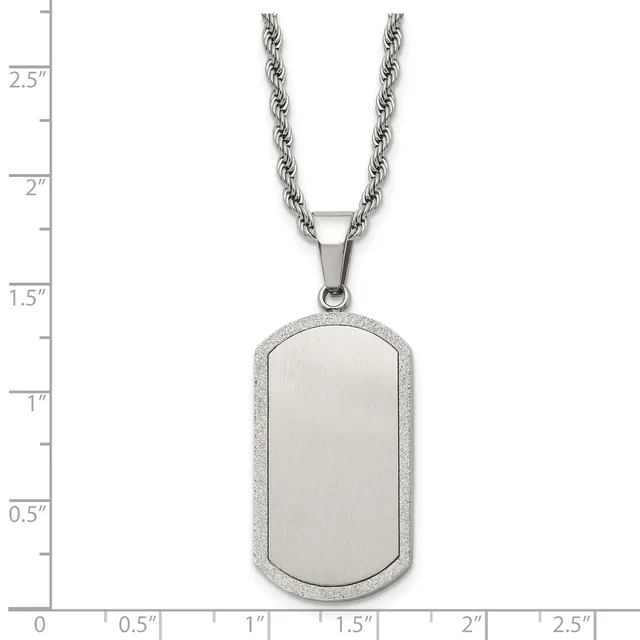 A stainless steel dog tag pendant with a brushed center and textured border hangs from a twisted rope chain against a measurement scale.