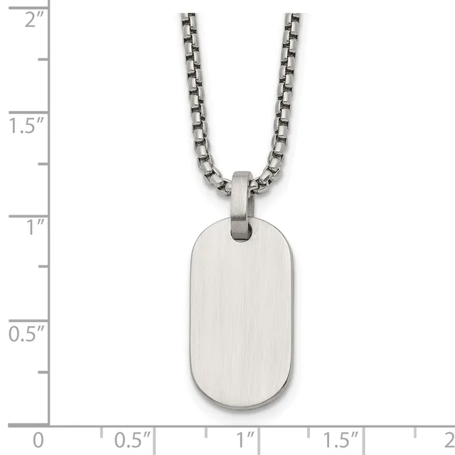 A stainless steel dog tag pendant with brushed finish hangs from a matching chain, shown against a ruler measuring approximately 1 inch wide by 1.75 inches tall.