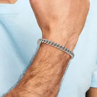 Man wearing a light blue shirt displaying a silver curb chain bracelet on his wrist.