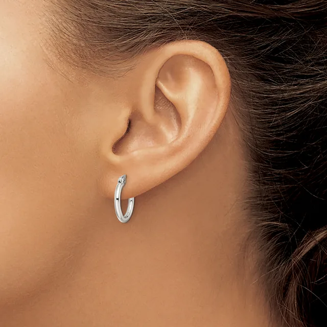 A woman wearing a small silver hoop earring in her earlobe, shown in profile against her neck and shoulder.