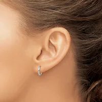 A person wearing small silver hoop earrings, shown from the side with brown hair pulled back to display the ear and earring.
