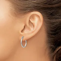 A person wearing a silver hoop earring in their earlobe, shown in profile from the side of their face and neck.