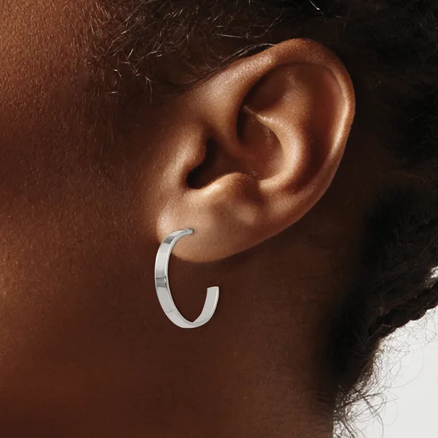 A silver hoop earring worn on the earlobe of a person with medium-toned skin.