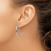 A silver hoop earring worn on the earlobe of a person with brown hair, shown from the side profile.