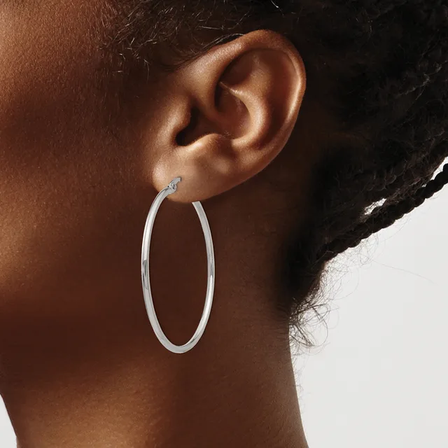 A person wearing a large oval silver hoop earring, shown in profile against a light background.