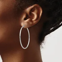 A person wearing a large oval silver hoop earring, shown in profile against a light background.