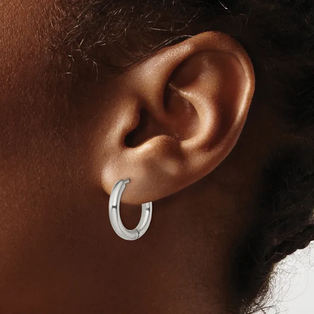 A silver hoop earring worn on the earlobe of a person with medium brown skin tone.