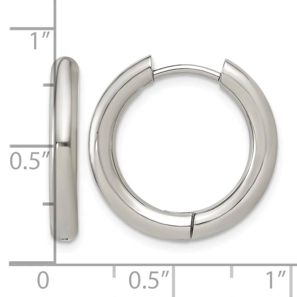 A pair of polished silver-colored chunky hoop earrings with a hinged closure, shown next to a ruler indicating they measure approximately one inch in diameter and half an inch in thickness.