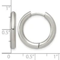 A pair of polished silver-colored chunky hoop earrings with a hinged closure, shown next to a ruler indicating they measure approximately one inch in diameter and half an inch in thickness.