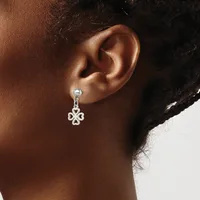 A silver drop earring with a four-pointed clover or flower design hangs from a stud post on a person's earlobe.