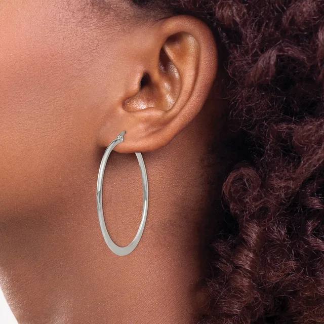 A person wearing a large oval silver hoop earring, shown in profile against their ear and shoulder.