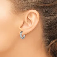 A person wearing small silver-toned hoop earrings with a grooved or textured surface, shown from the side view of their ear.