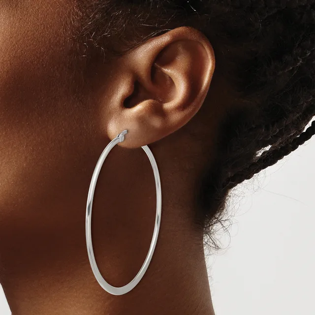 A person wearing a large silver oval hoop earring, shown from the side profile view of their ear and neck.