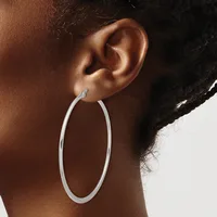 A person wearing a large silver oval hoop earring, shown from the side profile view of their ear and neck.