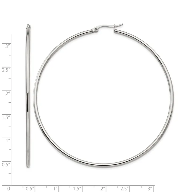 A pair of polished silver-toned hoop earrings displayed next to a ruler showing their diameter of approximately three inches.
