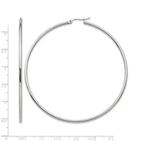A pair of polished silver-toned hoop earrings displayed next to a ruler showing their diameter of approximately three inches.